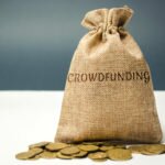 Money bag with coins with the word crowdfunding. Voluntary association of money or resources via the Internet. Support recipients. Financing start-up companies and small businesses. Co-investment